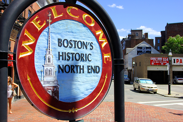 Three pairs of feet standing around the start of two lines of red brick on ground. Boston In A Day The Freedom Trail
